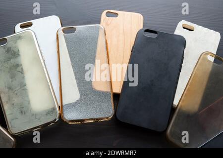 Pila di coprischiera in plastica multicolore per cellulare. Scelta di accessori per custodia protettiva per smartphone. Il telefono in silicone si trova sul retro nero Foto Stock