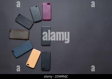 Pila di coprisedali in plastica multicolore per cellulare su sfondo nero. Scelta di accessori per la protezione dello smartphone. Un sacco di silicone telefono ba Foto Stock