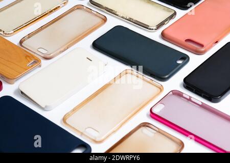 Pila di coprischiera in plastica multicolore per telefono cellulare. Scelta di accessori di protezione per smartphone su sfondo bianco. Un sacco di silicone telefono ba Foto Stock