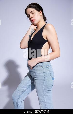 Giovane donna in cima nera isolata su viola Foto Stock