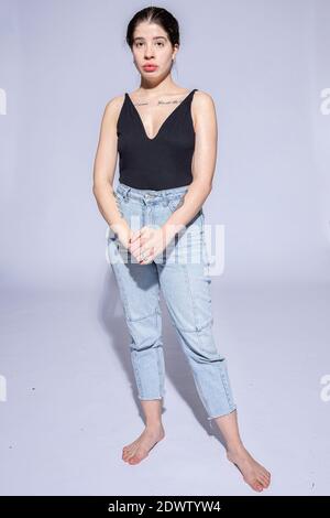 Bianca ragazza snella in jeans blu isolato su viola Foto Stock