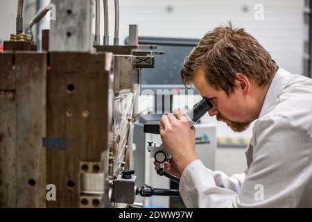 Uomo che controlla o esegue la manutenzione dello stampo a iniezione di plastica per la produzione di plastica, concetto industriale Foto Stock
