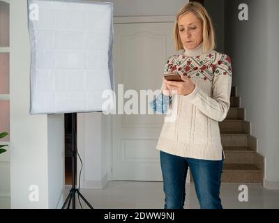 Un ritratto di una donna bionda di mezza età che tiene il suo cellulare e fare qualcosa con esso Foto Stock