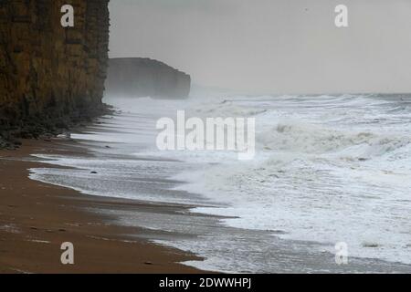 West Bay, Dorset, Regno Unito. 23 dicembre 2020. Regno Unito Meteo. I mari tempestosi si schiantano a riva sulla spiaggia di West Bay a Dorset in un pomeriggio di pioggia e forti venti raffinate. Picture Credit: Graham Hunt/Alamy Live News Foto Stock