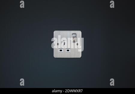 Presa elettrica di rete UK color argento con parete grigio scuro Foto Stock