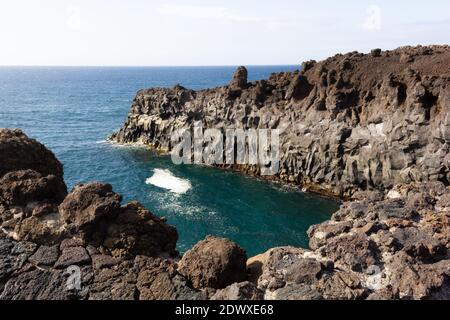 Costa vulcanica sul mare a Los Hervideros attrazione turistica in Lanzarote isola. L'acqua blu dell'oceano si tuffa sulle scogliere nere delle rocce Foto Stock