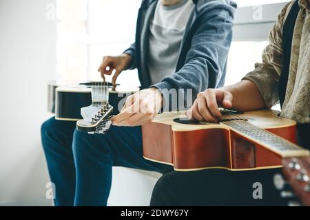 Imparare a suonare la chitarra. L'insegnante aiuta lo studente a sintonizzare la chitarra e spiega le basi per suonare la chitarra. Lezioni individuali di scuola domestica o extracurricolare. Foto Stock