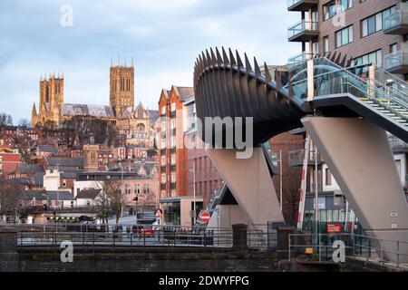 Un ponte pedonale sulla ferrovia nel Brayford Wharf East di Lincoln. Il ponte collega il complesso universitario con il centro città principale quando i treni sono in funzione e gli attraversamenti di livello sono giù. La Cattedrale può essere vista sullo sfondo con vista sulla città. Foto Stock