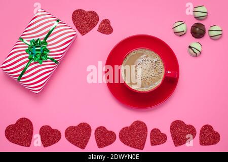 Romantico San Valentino con cuori rossi e tazza di caffè e cioccolato su sfondo di carta rosa, modello. Simbolo di San Valentino, vacanza romantica, vino Foto Stock
