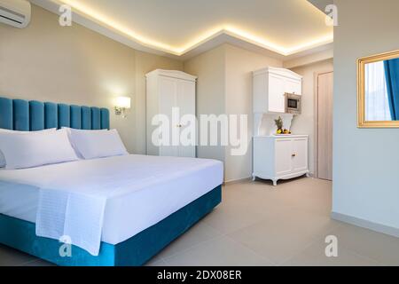 Interni in stile classico con camera da letto bianca e blu con cucina armadio a muro in appartamento doppia suite Foto Stock