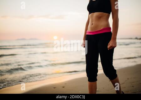 Donna corridore che fa jogging sulla spiaggia in un reggiseno sportivo top.Fit fitness donna formazione e allenarsi fuori come parte di Una sana lifestyle.Fitness donna runn Foto Stock