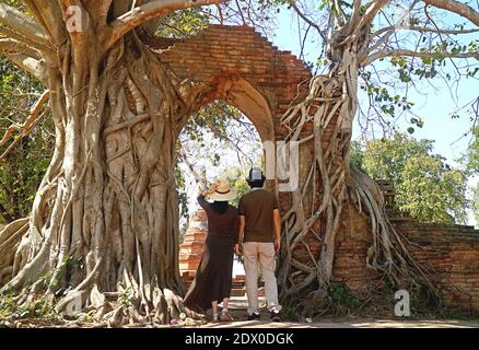 Coppia che entra nella sorprendente 'PORTA DEL TEMPO' delle rovine del Tempio di Wat Phra Ngam ad Ayutthaya, Thailandia Foto Stock