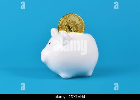 Moneta crypto dorata bitcoin bianco piggy banca su blu sfondo Foto Stock