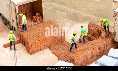 Lavoratori edili che scaricano mattoni, lavorando sul cantiere Foto Stock