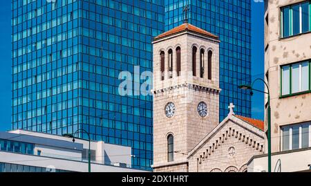 Architettura antica e nuova in Bosnia-Erzegovina, Europa. Antico e classico edificio della chiesa contro il nuovo edificio degli uffici. Foto Stock