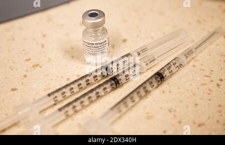 Un flaconcino di vaccino COVID-19 di Pfizer vicino a tre siringhe Foto Stock