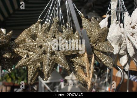 Scintillante decorazione di natale, in vendita su un mercato settimanale, stella d'oro per la decorazione dell'albero di natale. Foto Stock