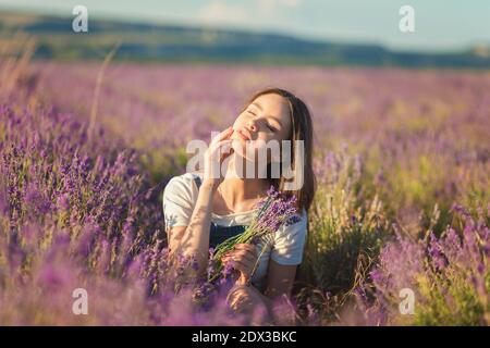 Bella ragazza giovane godendo la luce del sole in un campo di lavanda Foto Stock