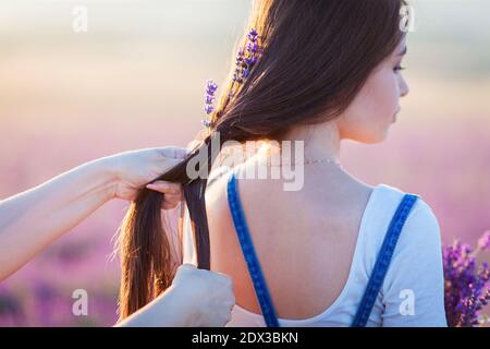 La mamma tesse i fiori di lavanda nei capelli di una figlia Foto Stock