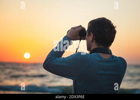 Un uomo che guarda attraverso binocoli in piedi sulla spiaggia Foto Stock