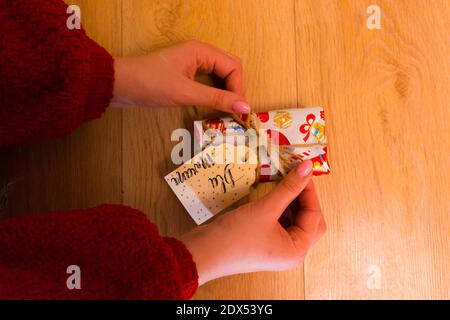 Una donna in pullover lavorato a maglia che legano un archetto di burlap intorno Un regalo di Natale Foto Stock