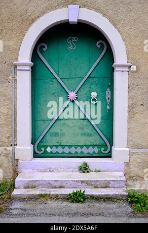 Porta in legno verde d'epoca piena di design in ferro ornato, con portico a volta Foto Stock