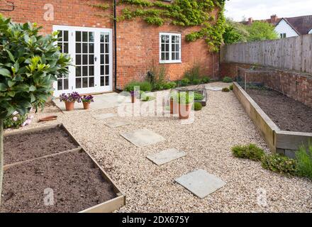 Giardino britannico in primavera con letti di verdure vuoti. Giardino vittoriano in stile cortile con ghiaia e pavimentazione in pietra di York Foto Stock