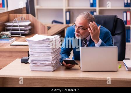 Il vecchio dipendente maschio è insoddisfatto del lavoro eccessivo sul posto di lavoro Foto Stock