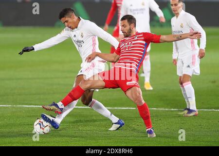 Madrid, Spagna. 23 dicembre 2020. Raphael Varane (L) del Real Madrid viena con Roberto Soldado di Granada durante una partita di calcio spagnola tra Real Madrid e Granada C.F. a Madrid, Spagna, il 23 dicembre 2020. Credit: Edward F. Peters/Xinhua/Alamy Live News Foto Stock
