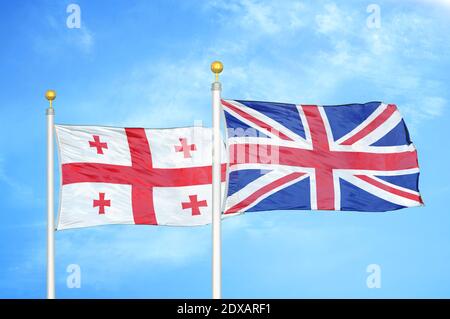 Georgia e Regno Unito due bandiere su flagpoli e blu cielo Foto Stock