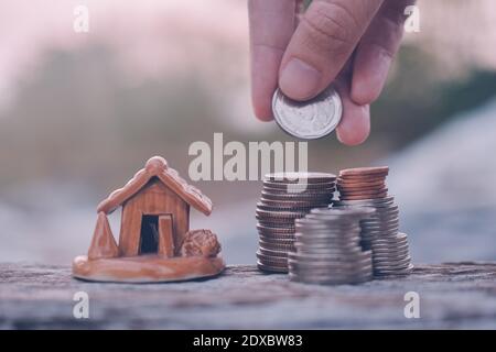 Mano selezionare monete impilare modello casa su tavola di legno Foto Stock