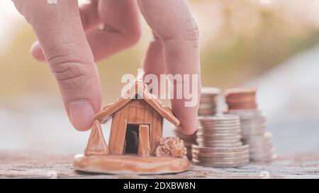 Mano selezionare monete impilare modello casa su tavola di legno Foto Stock