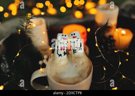 Marshmallow manna di neve nella tazza di caffè, bokeh luci, decorazioni natalizie Foto Stock