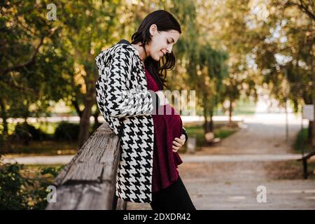 Donna incinta che tocca lo stomaco mentre si trova in parcheggio Foto Stock