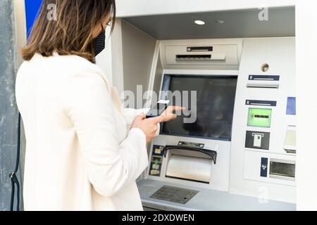 L'imprenditore femminile preleva denaro dagli ATM durante il COVID-19 Foto Stock