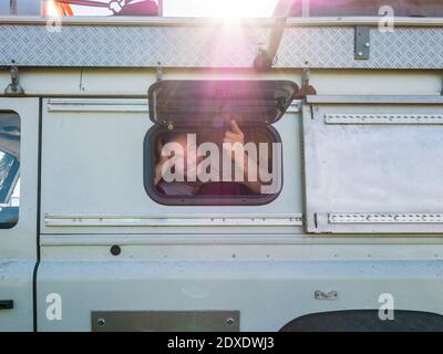 Ritratto di escursionista maschile guardando la fotocamera attraverso la finestra di veicolo fuoristrada Foto Stock