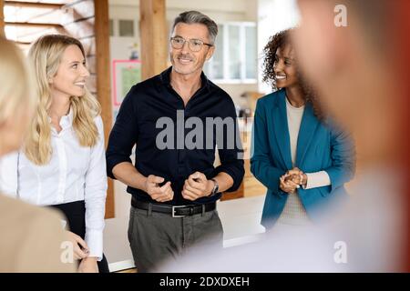 Uomo d'affari maturo che parla con i colleghi mentre si trova in ufficio Foto Stock