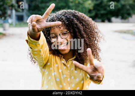 Donna spensierata che mostra un gesto di pace mentre si trova sul sentiero Foto Stock