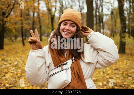 Felice giovane donna pace gesturing in autunno parco Foto Stock