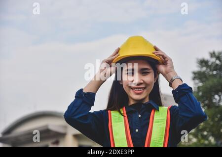 Donne Ingegneria toccare su elmetto di sicurezza in piedi luogo di lavoro esterno Foto Stock