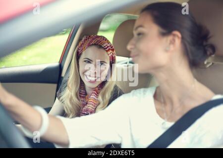 Sorridendo gli amici che parlano mentre si guida in auto durante un viaggio su strada Foto Stock