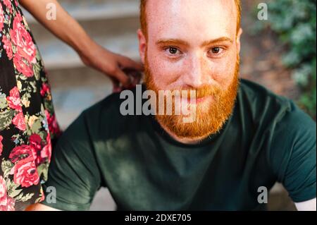 Uomo bearded seduto da fidanzata in parco Foto Stock