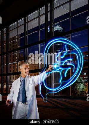 Ginecologo maschile luce che concatena utero con feto in ospedale Foto Stock