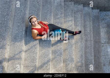 Giovane sportiva con gamba protesica che si rilassa mentre si siede sui gradini Foto Stock