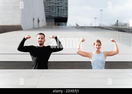 Atleti che mostrano i muscoli mentre si levano in piedi dalla parete di ritegno Foto Stock