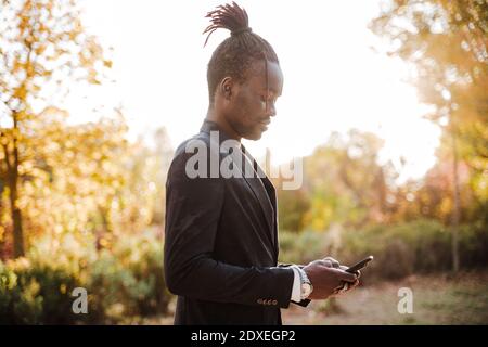 Uomo elegante che usa lo smartphone nel parcheggio Foto Stock