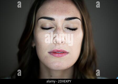 Giovane donna con gli occhi chiusi in studio Foto Stock