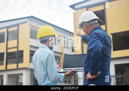 Due tecnici utilizzano la presentazione di notebook computer sul luogo di lavoro edificio edificio di background costruzione Foto Stock