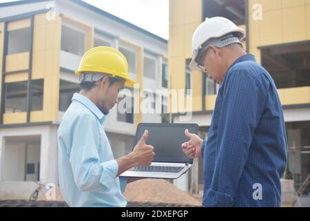Due tecnici utilizzano la presentazione di notebook computer sul luogo di lavoro edificio edificio di background costruzione Foto Stock