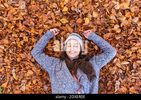 Sorridente escursionista sdraiato sulle foglie autunnali a Cannock Chase bosco Foto Stock